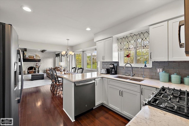kitchen featuring stainless steel appliances, open floor plan, a sink, dark wood-style flooring, and a chandelier