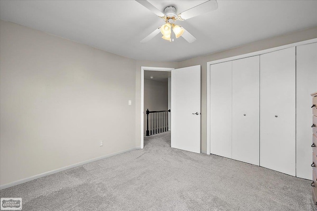 unfurnished bedroom with carpet flooring, a closet, baseboards, and a ceiling fan