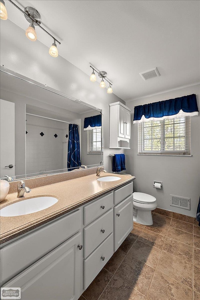 bathroom featuring a shower with curtain, double vanity, and toilet