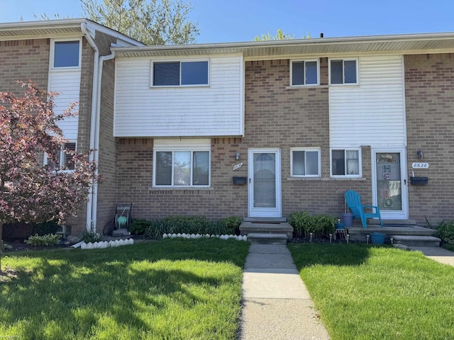 townhome / multi-family property featuring a front yard and brick siding