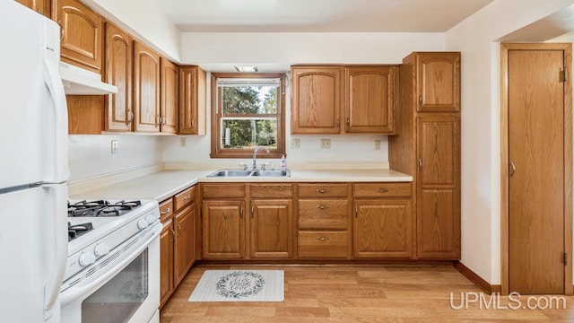 kitchen featuring a sink, white appliances, under cabinet range hood, and brown cabinetry