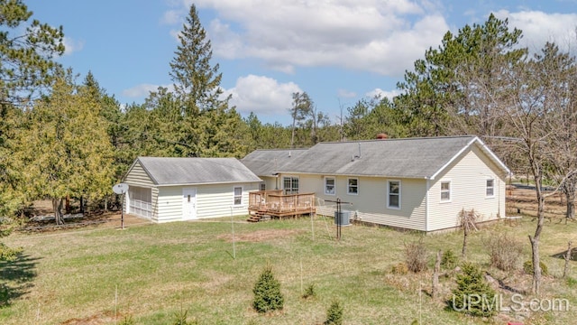 rear view of house featuring a wooden deck, an outbuilding, a lawn, and cooling unit