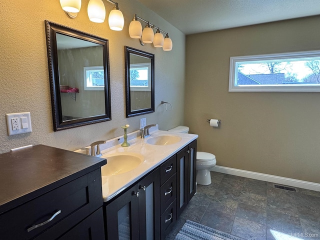 6403 N 1st St, Wells, MI 49894 - bathroom with healthy amount of natural light, baseboards, toilet, and double vanity