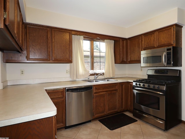 kitchen featuring appliances with stainless steel finishes, a sink, light countertops, and light tile patterned flooring