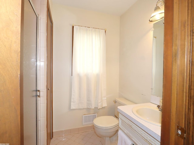 bathroom with toilet, vanity, an enclosed shower, and baseboards