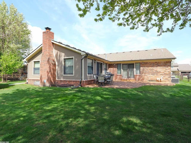 rear view of house with a chimney, a patio area, brick siding, and central AC