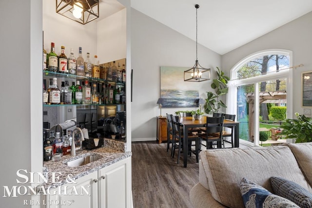 indoor wet bar featuring a chandelier, wood finished floors, high vaulted ceiling, and hanging light fixtures