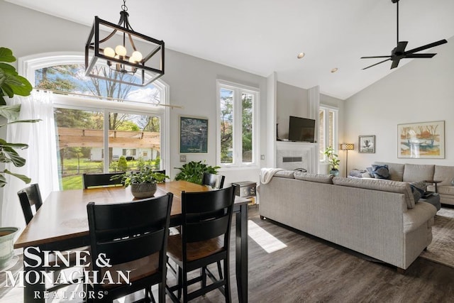 dining area with a chandelier, dark wood-style flooring, a fireplace, high vaulted ceiling, and recessed lighting