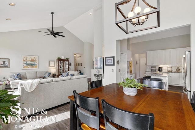 dining room with high vaulted ceiling, a ceiling fan, dark wood-type flooring, and a chandelier
