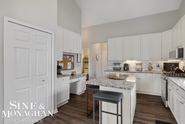 kitchen with stainless steel appliances, white cabinets, high vaulted ceiling, and decorative backsplash