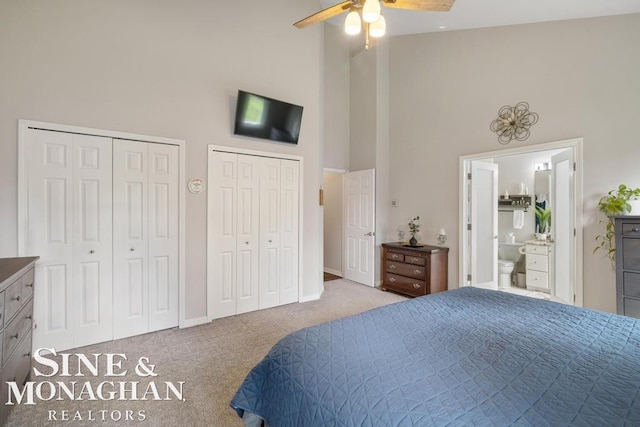bedroom with high vaulted ceiling, carpet flooring, multiple closets, a ceiling fan, and ensuite bath