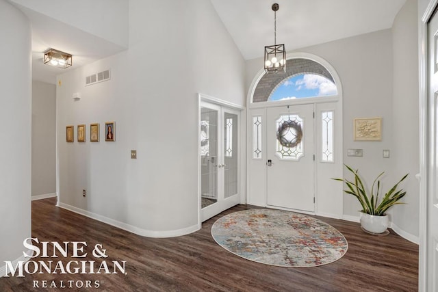 foyer entrance featuring high vaulted ceiling, a chandelier, wood finished floors, and baseboards