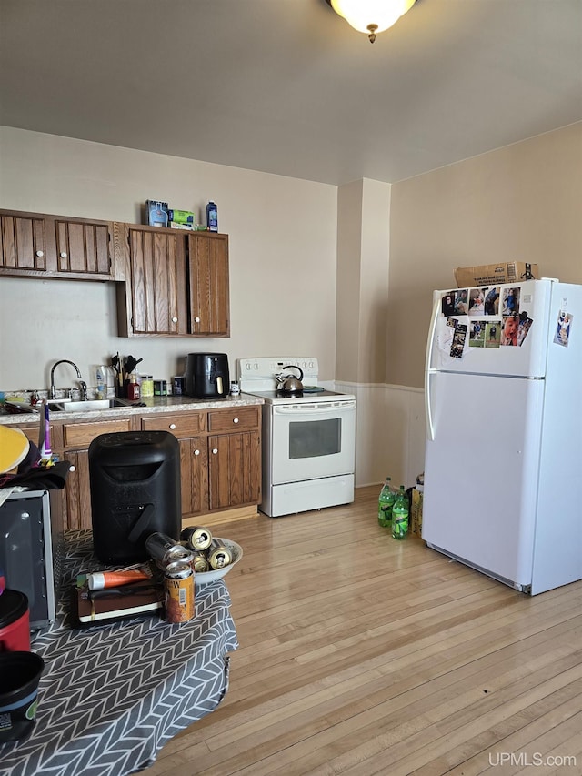 118 S Tamarack St, Laurium, MI 49913 - kitchen with white appliances, a sink, brown cabinets, light wood-type flooring, and light countertops
