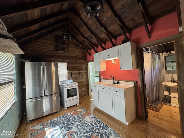 kitchen with high end refrigerator, white gas range oven, wooden walls, wooden ceiling, and plenty of natural light