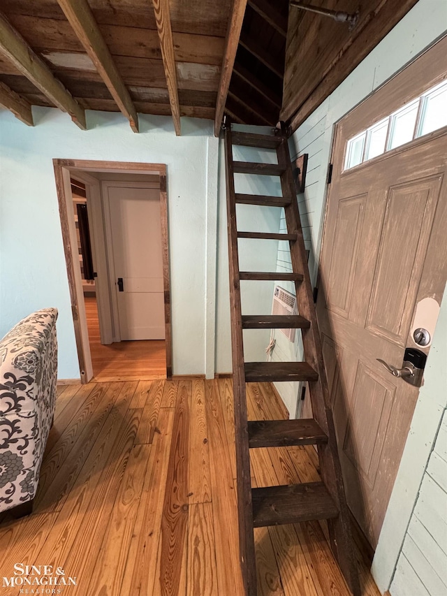 staircase featuring wood finished floors, beam ceiling, and wood ceiling
