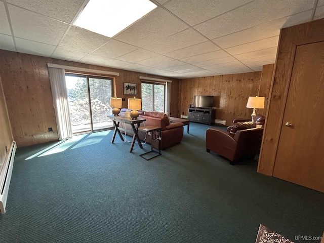 3260 Herron Dr, Gwinn, MI 49841 - living room featuring carpet flooring, wooden walls, a paneled ceiling, and a baseboard heating unit