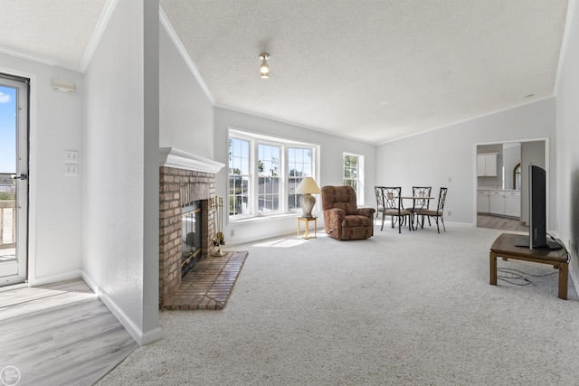 carpeted living area with ornamental molding, baseboards, a brick fireplace, vaulted ceiling, and a textured ceiling