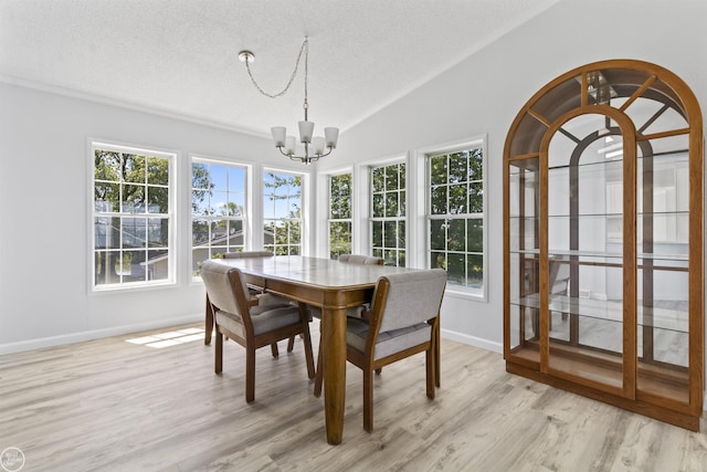 dining room featuring a chandelier, a textured ceiling, light wood finished floors, baseboards, and lofted ceiling