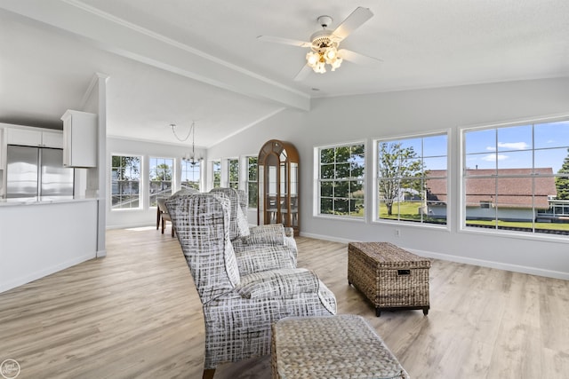 living area with a chandelier, light wood finished floors, baseboards, and ceiling fan