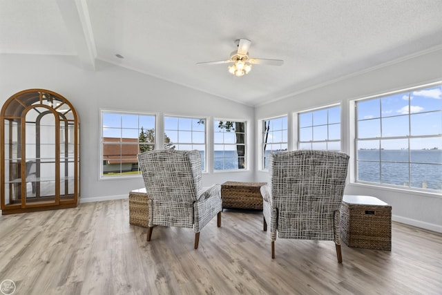 sitting room with a ceiling fan, wood finished floors, baseboards, and a water view