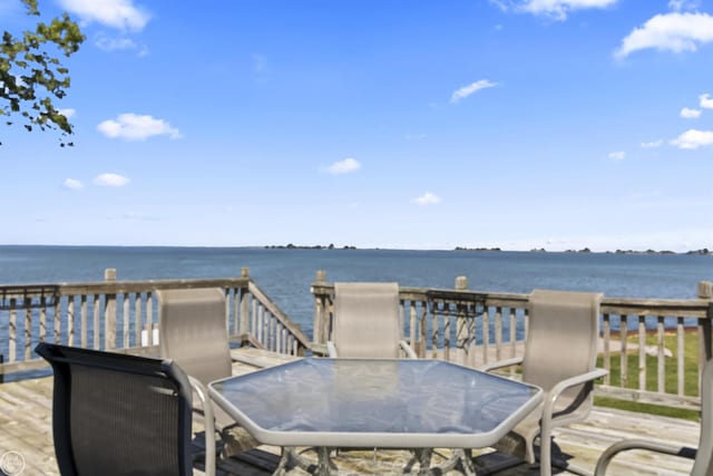 wooden terrace with outdoor dining area and a water view