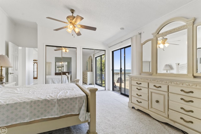 bedroom with access to exterior, lofted ceiling, two closets, ceiling fan, and a textured ceiling