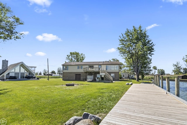 dock featuring a lawn, a deck with water view, and stairway