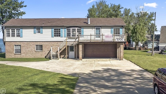 rear view of property with concrete driveway, brick siding, stairs, a yard, and a garage