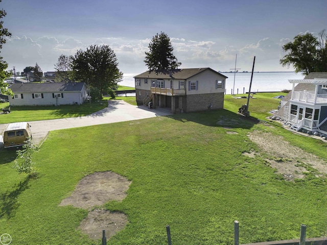 view of grassy yard with a water view and driveway
