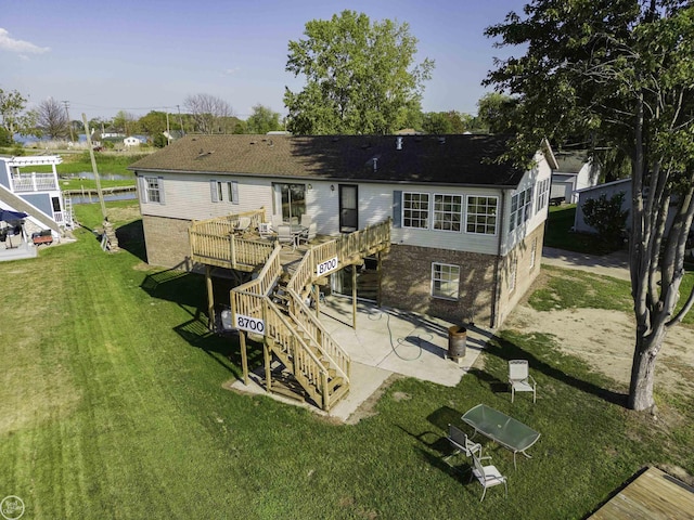 rear view of property featuring stairway, a wooden deck, a patio, a yard, and brick siding
