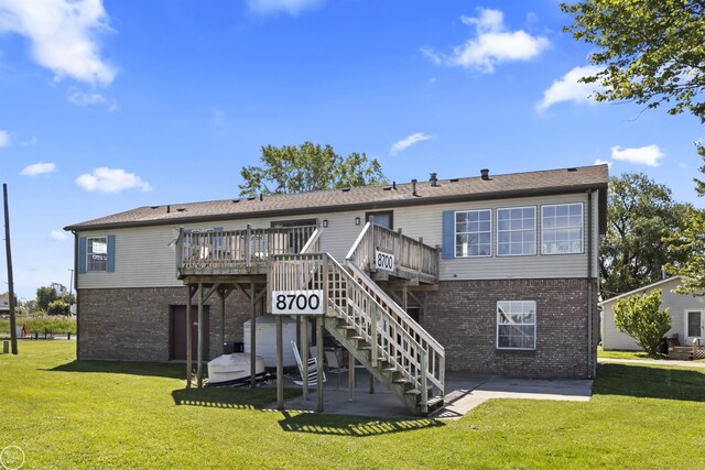 back of house featuring brick siding, a deck, a patio area, and a lawn