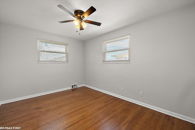 empty room featuring healthy amount of natural light, baseboards, and wood finished floors