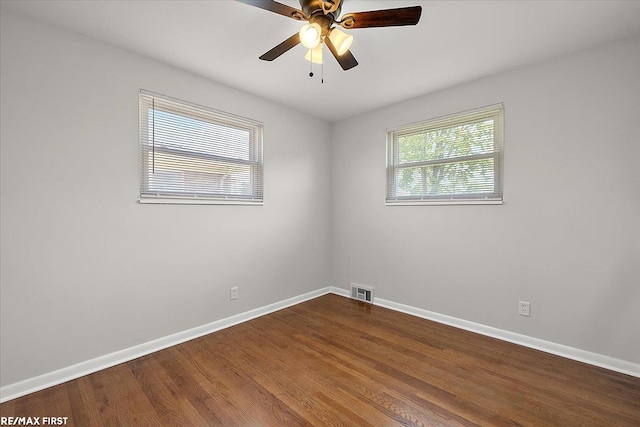 unfurnished room with baseboards, dark wood-style floors, and ceiling fan