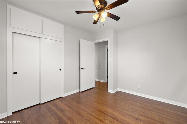 unfurnished bedroom featuring wood finished floors, baseboards, a closet, and a ceiling fan