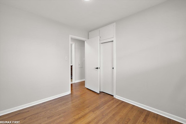 unfurnished bedroom with baseboards, light wood-style flooring, and a closet