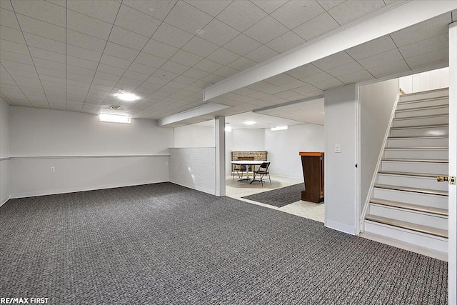 finished basement with carpet flooring, stairs, baseboards, and bar area