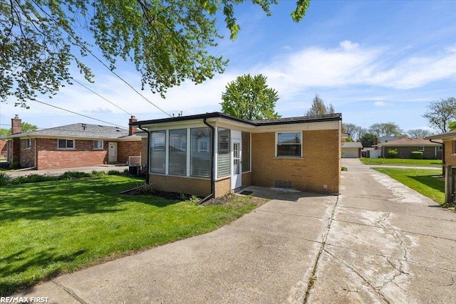 view of front of property with brick siding, a front yard, and driveway