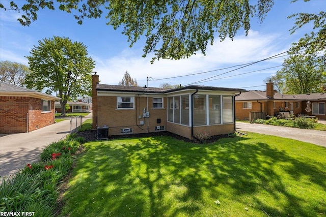 rear view of property featuring a chimney, brick siding, and a sunroom