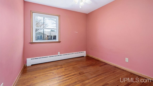 606 S 13th St, Gladstone, MI 49837 - empty room featuring a baseboard heating unit, baseboards, wood finished floors, and ceiling fan