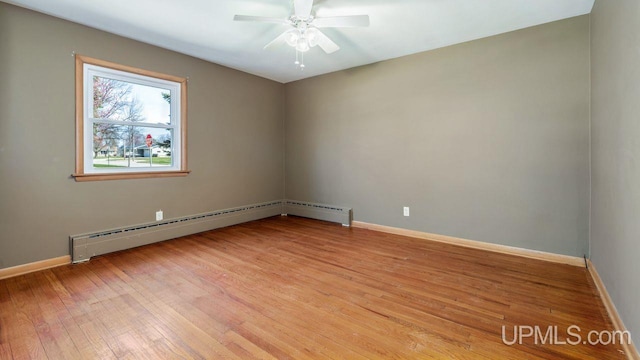 606 S 13th St, Gladstone, MI 49837 - spare room featuring light wood-style flooring, baseboards, a ceiling fan, and a baseboard heating unit