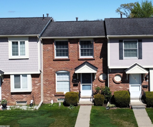 view of property featuring brick siding and a front yard