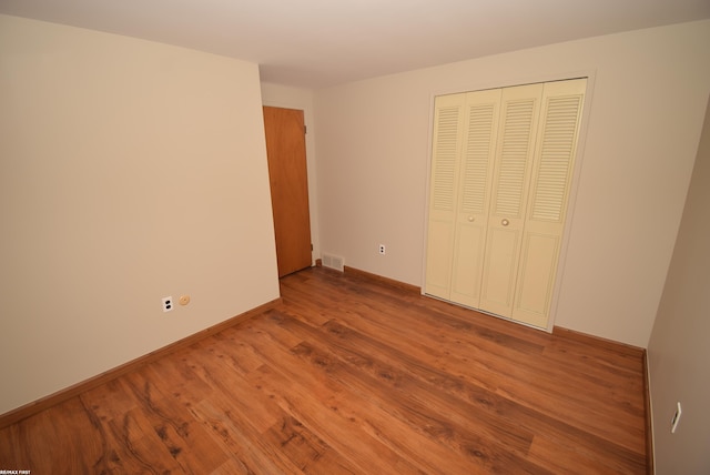 unfurnished bedroom with wood finished floors, a closet, and baseboards