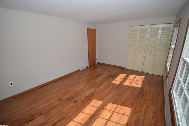 unfurnished bedroom with wood finished floors, baseboards, and a closet