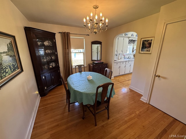 1100 Poplar Ave, Crystal Falls, MI 49920 - dining space with arched walkways, light wood-style floors, a chandelier, and baseboards
