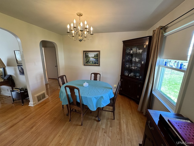 1100 Poplar Ave, Crystal Falls, MI 49920 - dining room with arched walkways, light wood finished floors, a chandelier, and baseboards