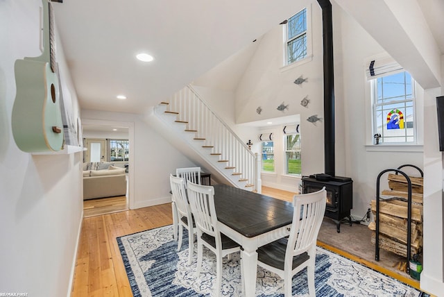 dining room with stairway, wood-type flooring, a wood stove, and recessed lighting