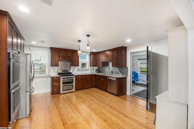 kitchen featuring appliances with stainless steel finishes, light wood-style floors, recessed lighting, healthy amount of natural light, and hanging light fixtures
