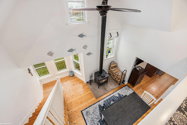 living area featuring a wood stove, a high ceiling, healthy amount of natural light, hardwood / wood-style floors, and ceiling fan