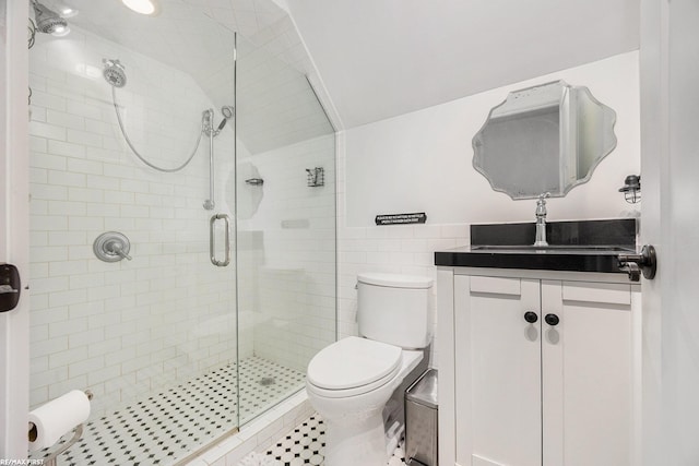 full bathroom with a stall shower, vanity, toilet, tile walls, and lofted ceiling