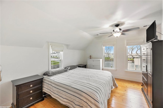 bedroom with light wood finished floors, vaulted ceiling, baseboards, and ceiling fan